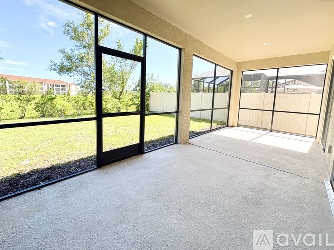 A room with large windows and a view of a grassy area and buildings outside.