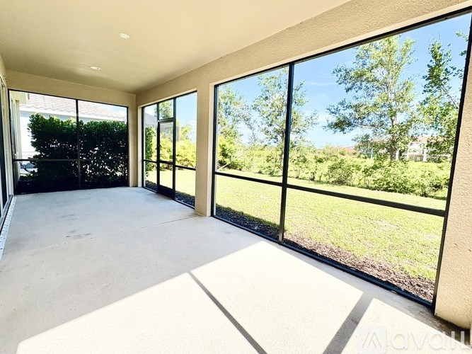A sunny day in a spacious room with large windows overlooking a green lawn.