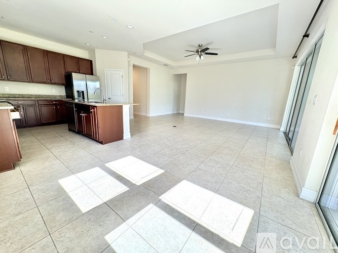 A spacious kitchen and living room with a ceiling fan and tiled flooring.