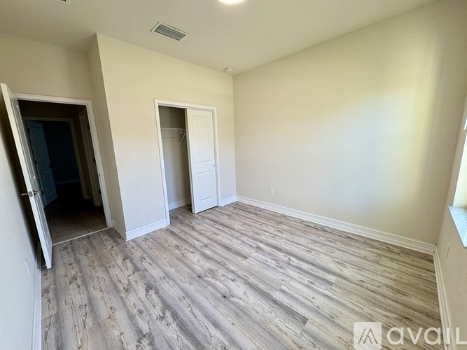 A room with wood flooring and two doors, one of which is open.