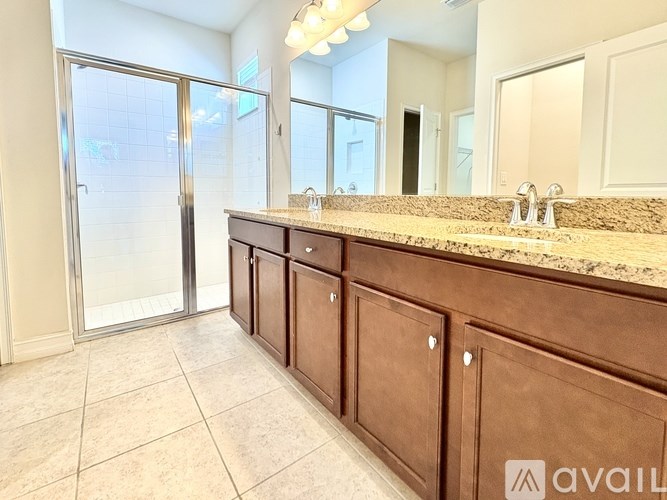 A bathroom with a granite countertop and a walk-in shower.