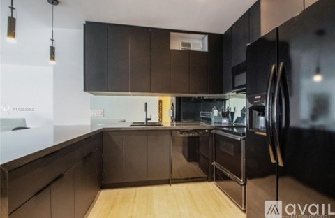 A modern kitchen with dark brown cabinets and a black refrigerator.