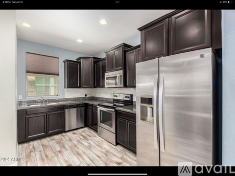 A modern kitchen with dark brown cabinets and stainless steel appliances.