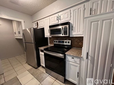 A kitchen with white cabinets and a black stove top oven.