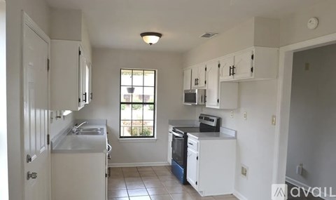 A kitchen with white cabinets and a window.