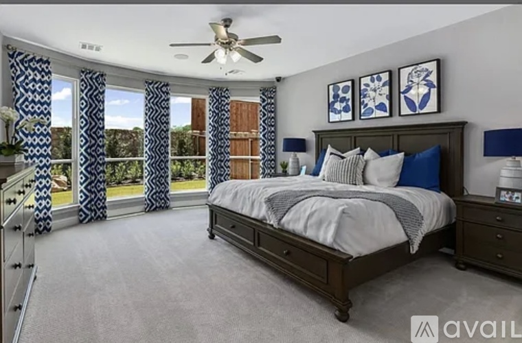 A bedroom with a large bed and a ceiling fan.