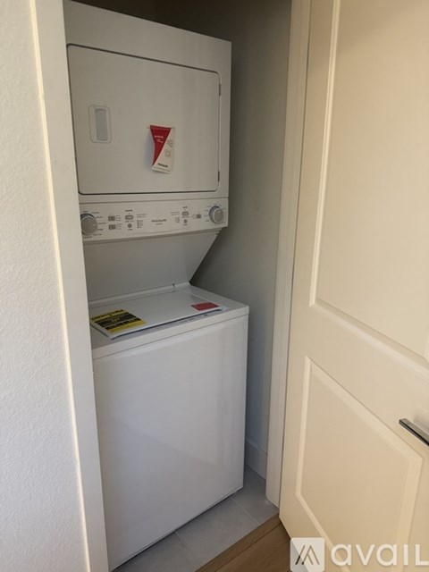A white dishwasher is in a narrow space between a wall and a door.