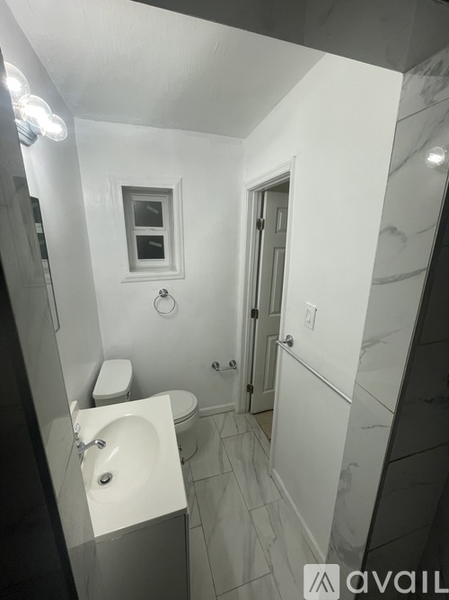 A bathroom with a toilet, sink, and mirror.