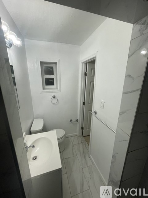 A bathroom with a toilet, sink, and mirror.