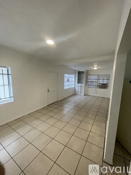 A spacious room with tiled flooring and a window on the left side.