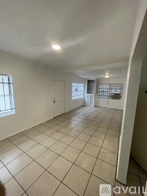 A spacious room with tiled flooring and a window on the left side.