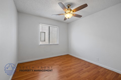 A room with a ceiling fan and a window with blinds.