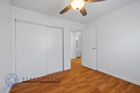 A room with a ceiling fan and wooden floors.