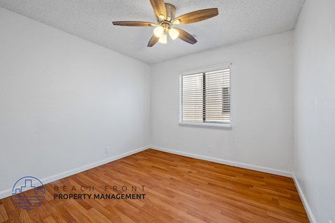 A room with a ceiling fan and wooden flooring.