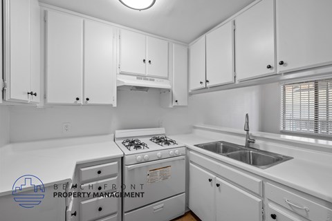 A kitchen with white cabinets and appliances.