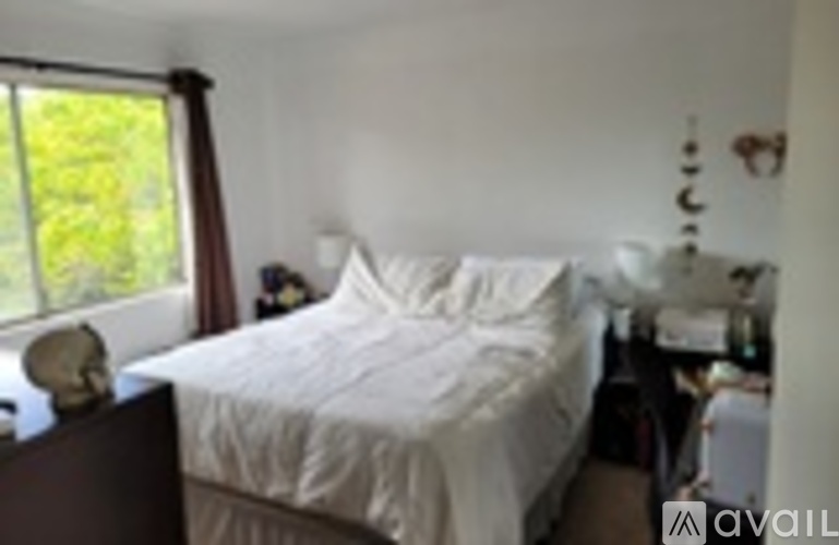 A bedroom with a bed, nightstand, and window.