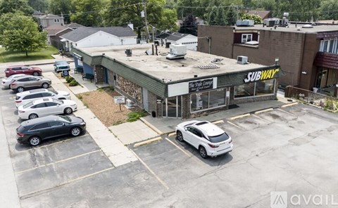 A SUBWAY restaurant is located in a parking lot.