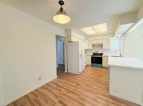 A kitchen with a white counter and a wooden floor.
