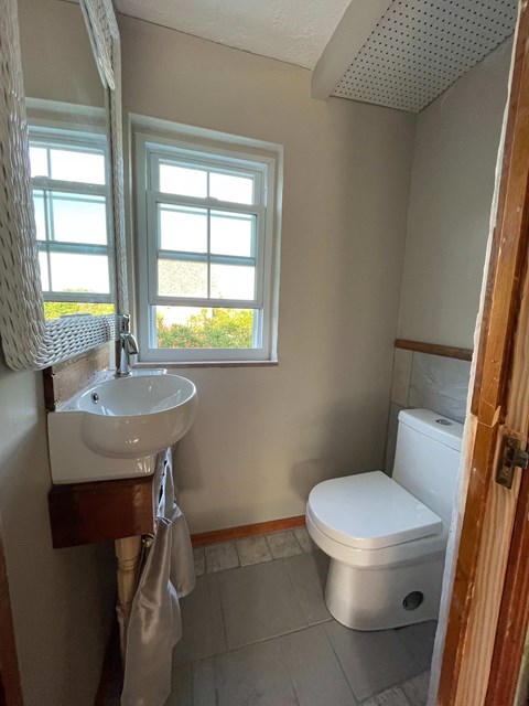 A small bathroom with a toilet, sink, and window.