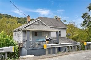 A house with a grey roof and a grey wall with a white window and a mailbox.