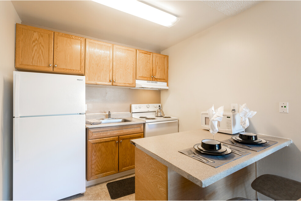 A kitchen with a white refrigerator and wooden cabinets.