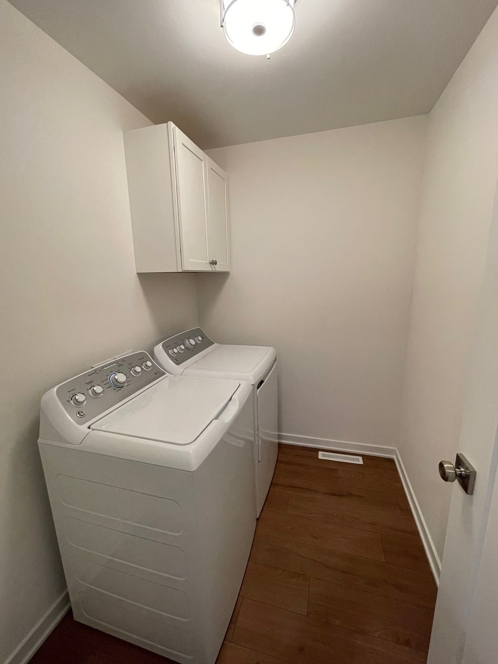 A small white washing machine sits in a small room.