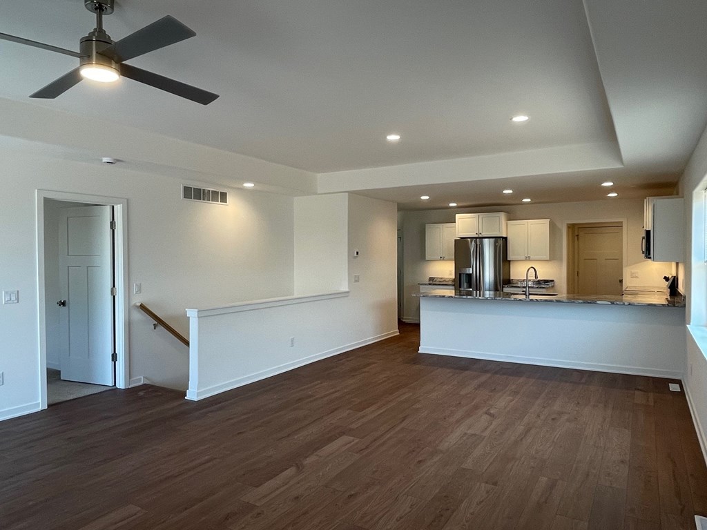 A room with a ceiling fan and wooden flooring.
