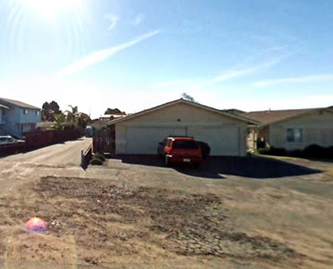 A red car is parked in front of a house.