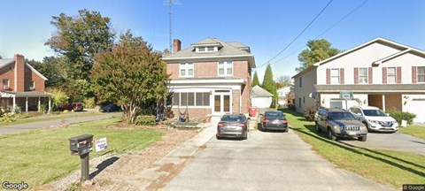 A street view of a residential area with houses and parked cars.