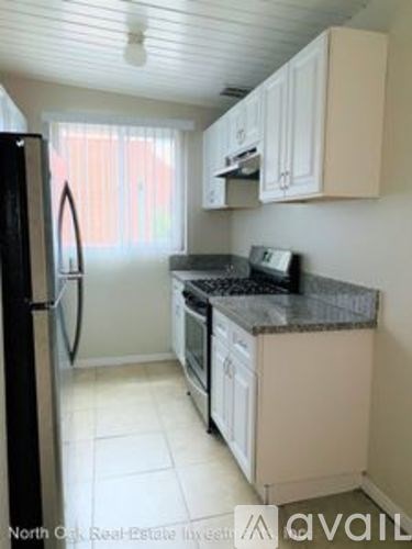 A kitchen with white cabinets and a black fridge.