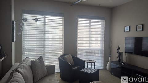 A living room with a grey couch, a black armchair, and a television on the wall.
