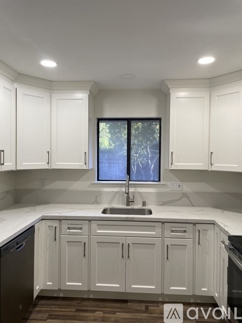 A kitchen with white cabinets and a window.