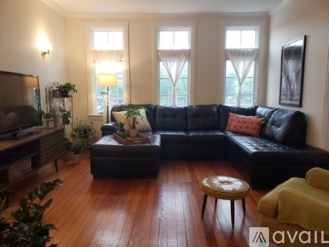 A living room with a black couch and a wooden floor.