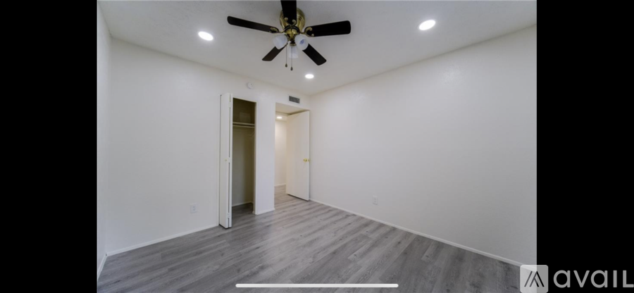 A spacious room with a ceiling fan and wooden flooring.