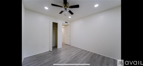 A spacious room with a ceiling fan and wooden flooring.