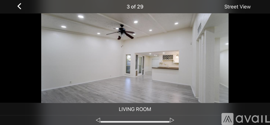 A spacious living room with a ceiling fan and lighting.