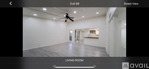 A spacious living room with a ceiling fan and lighting.