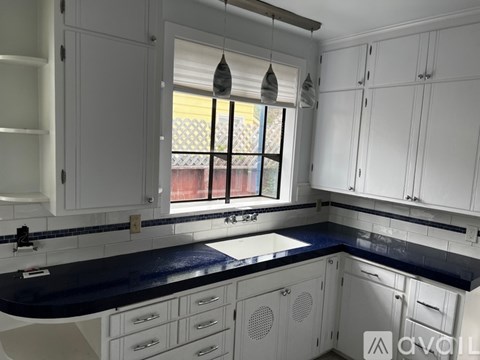 A kitchen with white cabinets and a black countertop.