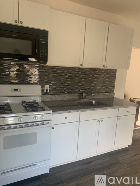 A kitchen with white cabinets and a black microwave above the stove.