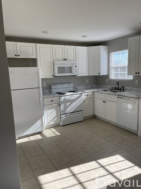 A kitchen with white appliances and cabinets.