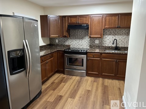 A kitchen with wooden cabinets and a stainless steel refrigerator.