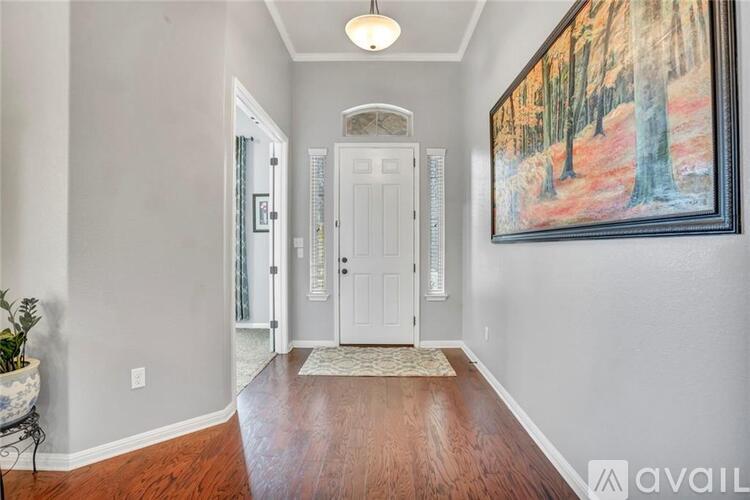 A hallway with a painting on the wall and a rug on the floor.