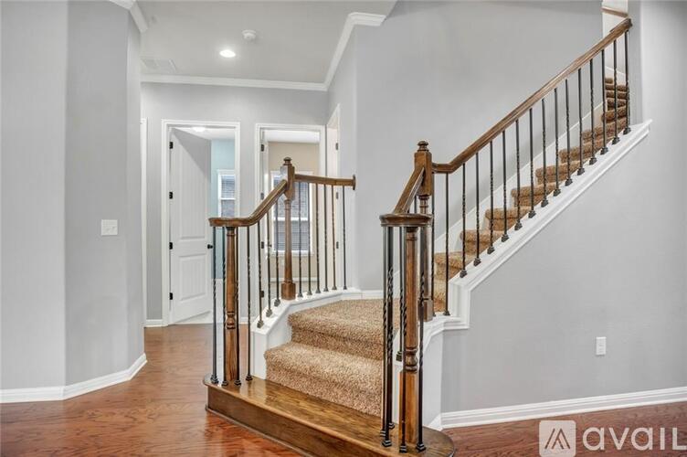 A staircase with a wooden handrail and a beige carpeted runner.