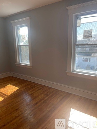 A room with wooden floors and two windows.