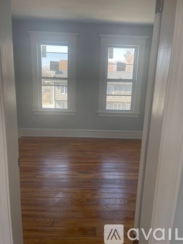 A room with two windows and wooden flooring.