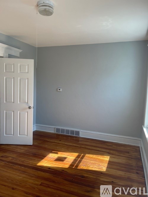 A room with a white door and wooden floor.