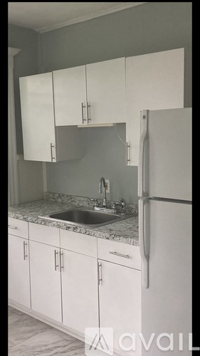 A kitchen with white cabinets and a refrigerator.