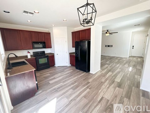 A kitchen with wooden cabinets and a black fridge.