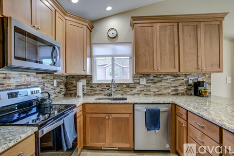 A kitchen with wooden cabinets and a stone backsplash.