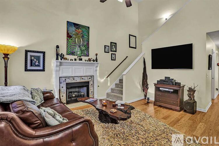 A living room with a brown leather couch, a fireplace, and a television.